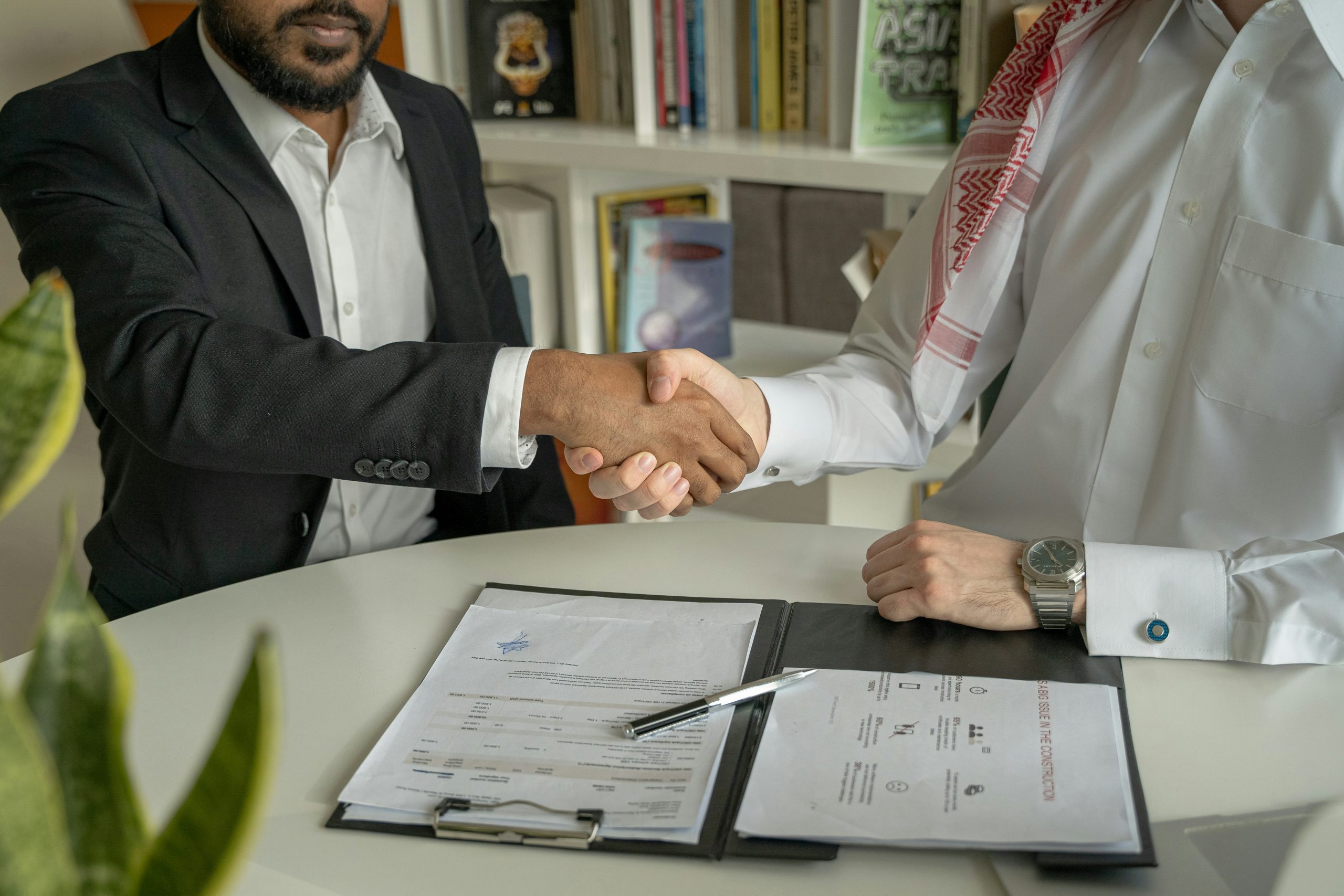 Two business people shaking hands over a contract document