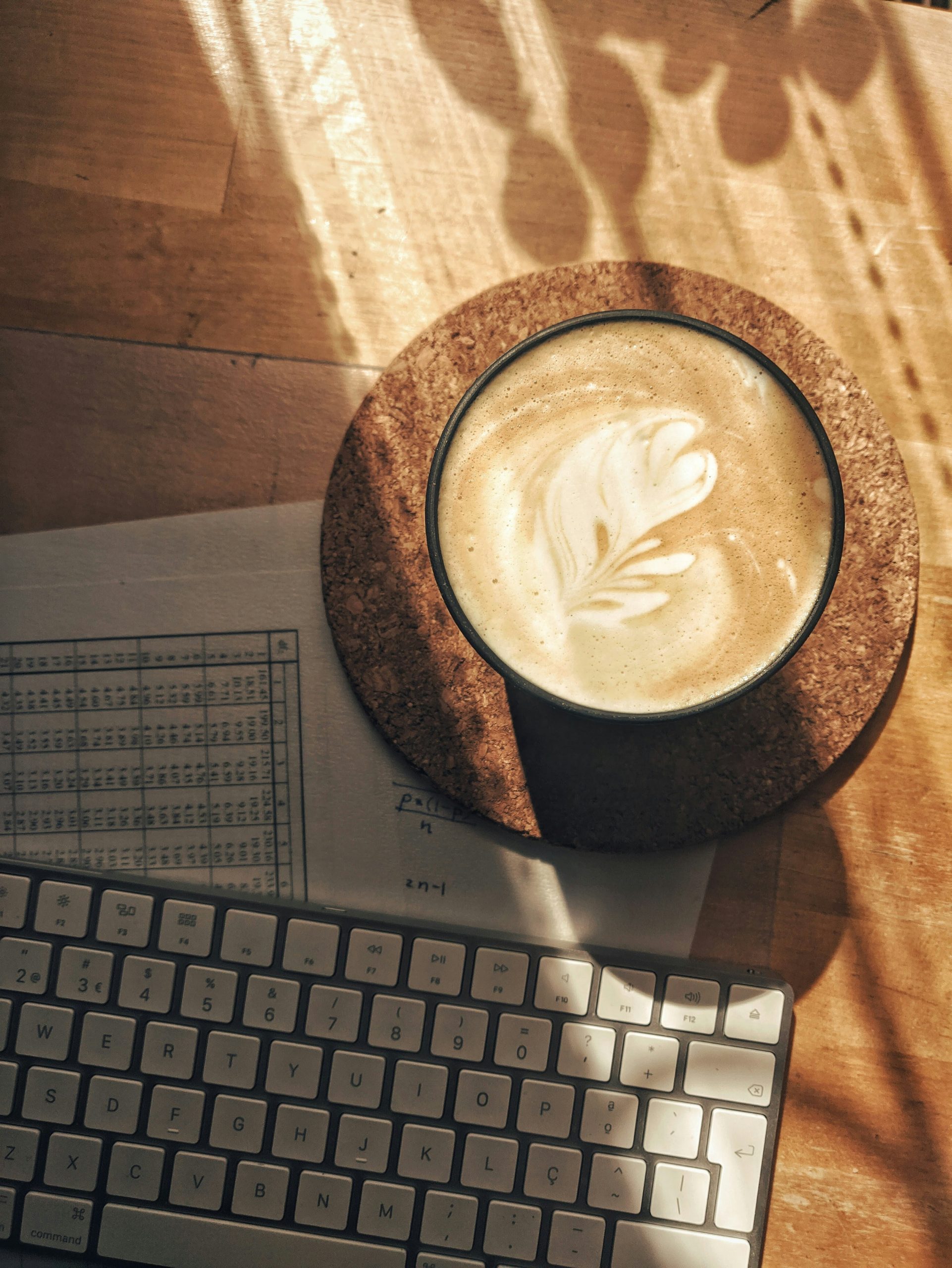 Hands typing on a laptop with WordPress logo on screen and coffee cup on a wooden table