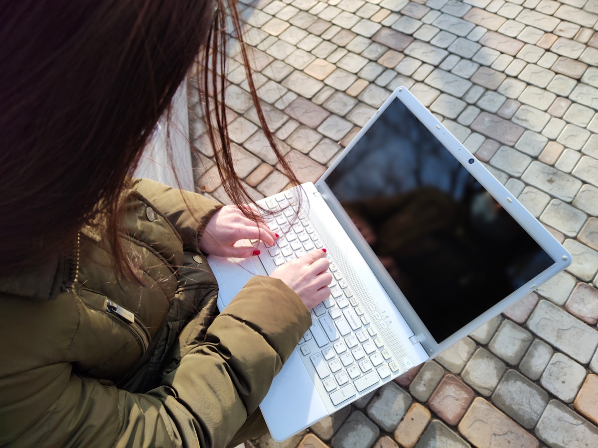 a woman is typing on her laptop outside