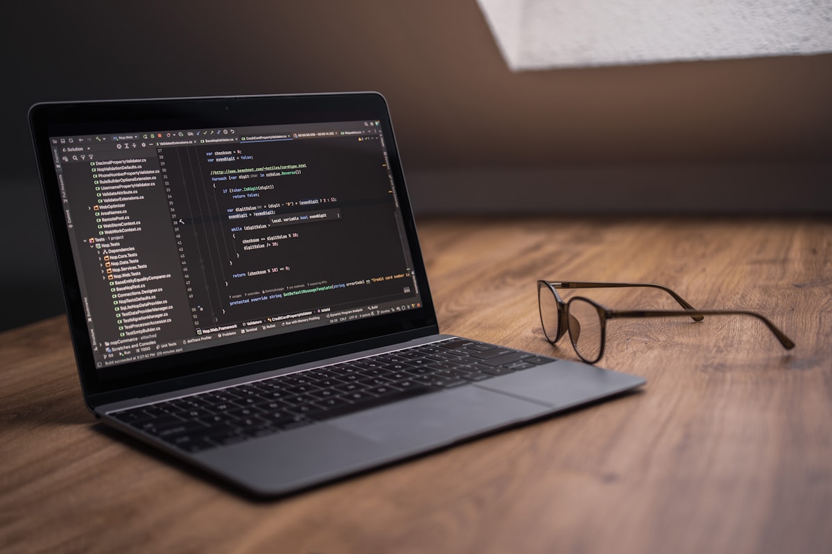Laptop displaying code with glasses on desk