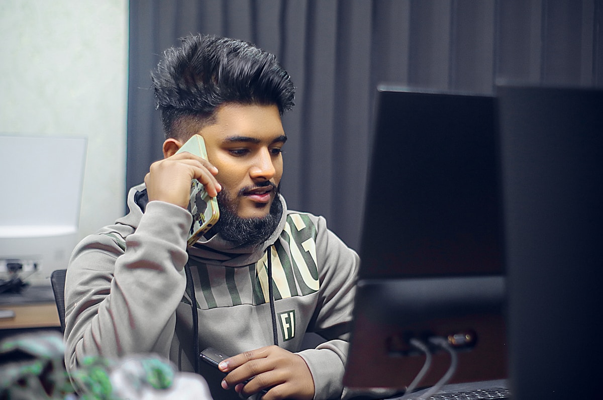 Un homme est au téléphone devant un ordinateur.
