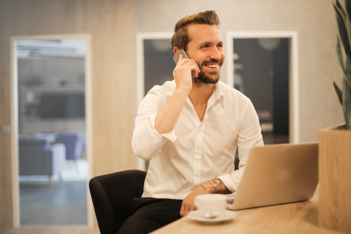 Un homme utilise un smartphone assis sur une chaise.