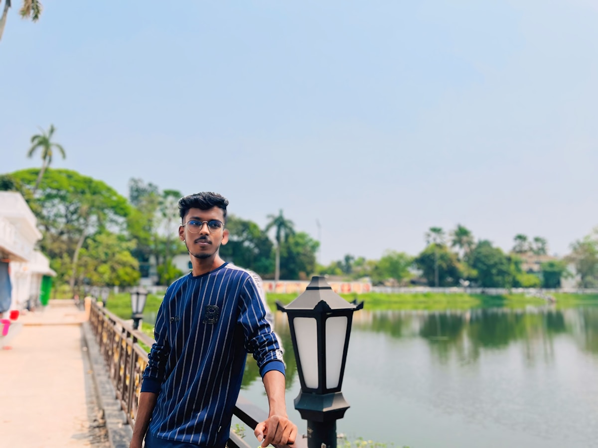 Un homme debout près d'un lampadaire au bord de l'eau.