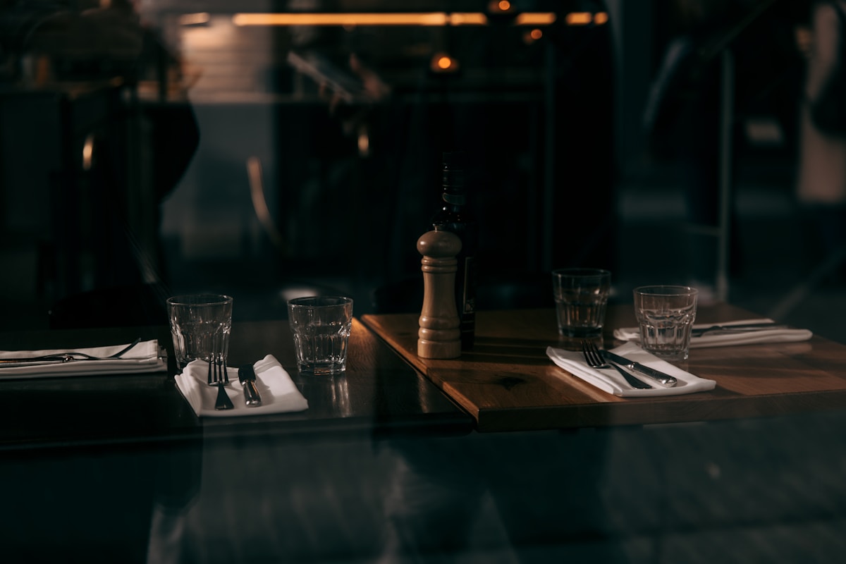 Table de restaurant sombre avec verres et couverts.
