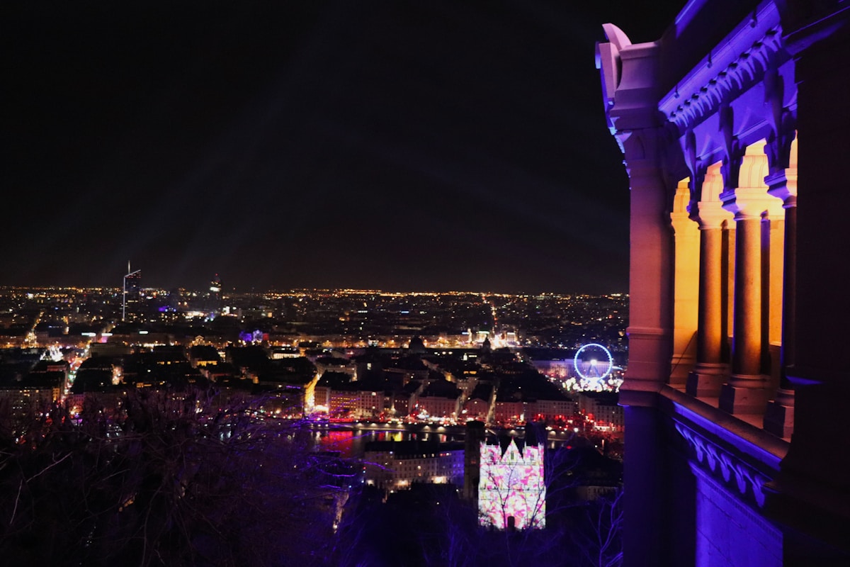 Ville illuminée de nuit, avec une grande roue et des bâtiments éclairés.