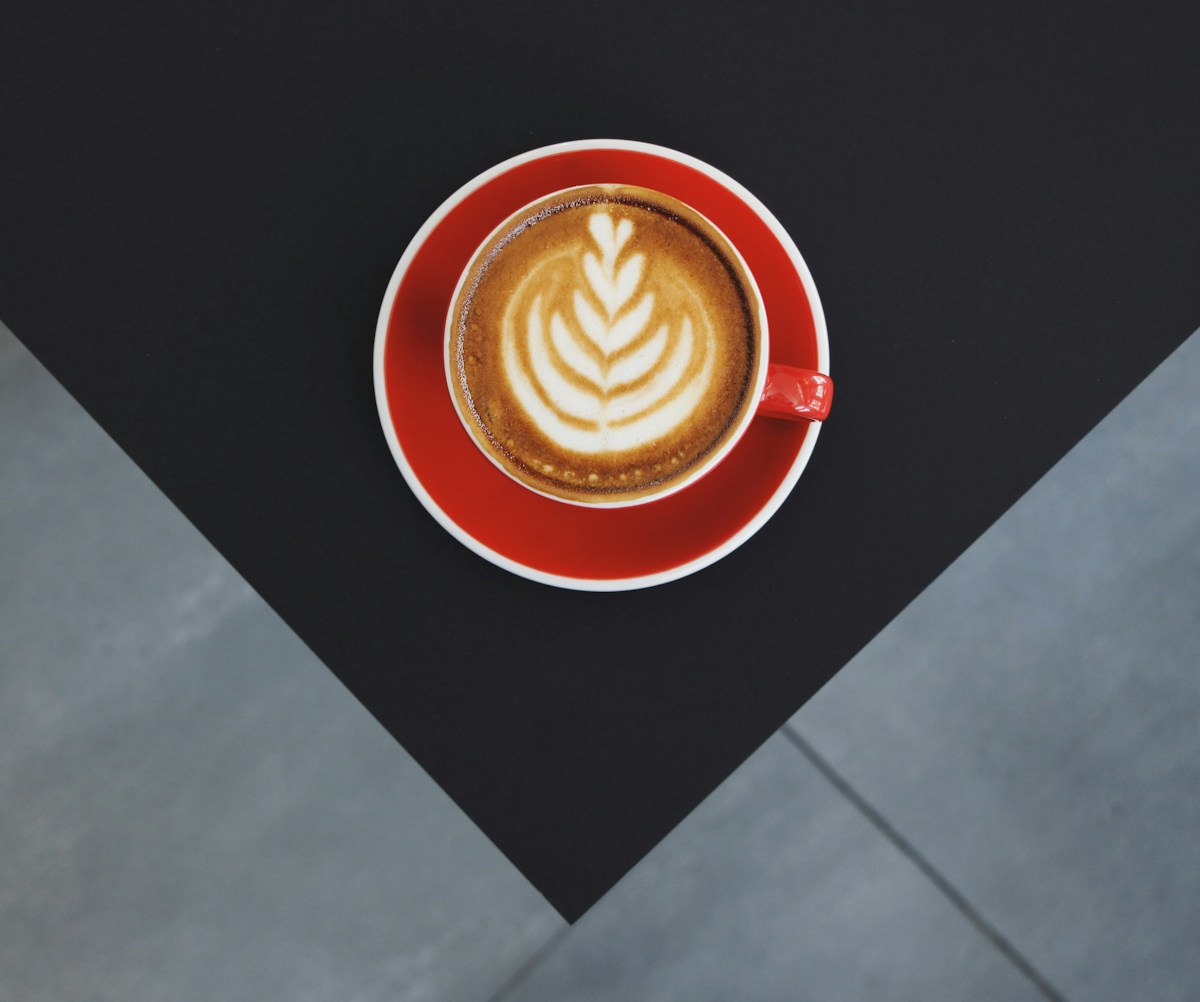 Une tasse en céramique rouge et blanche remplie de café.
