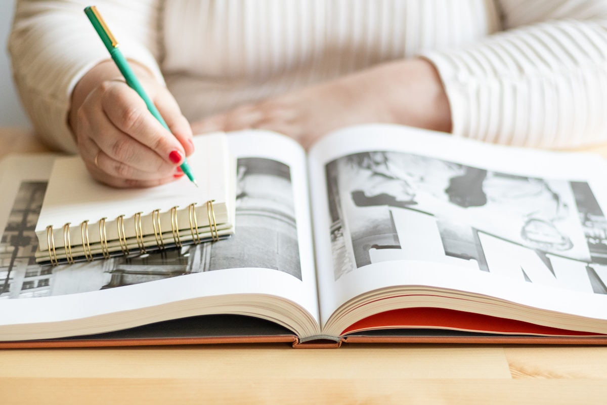 Une personne tenant un stylo et écrivant dans un livre.